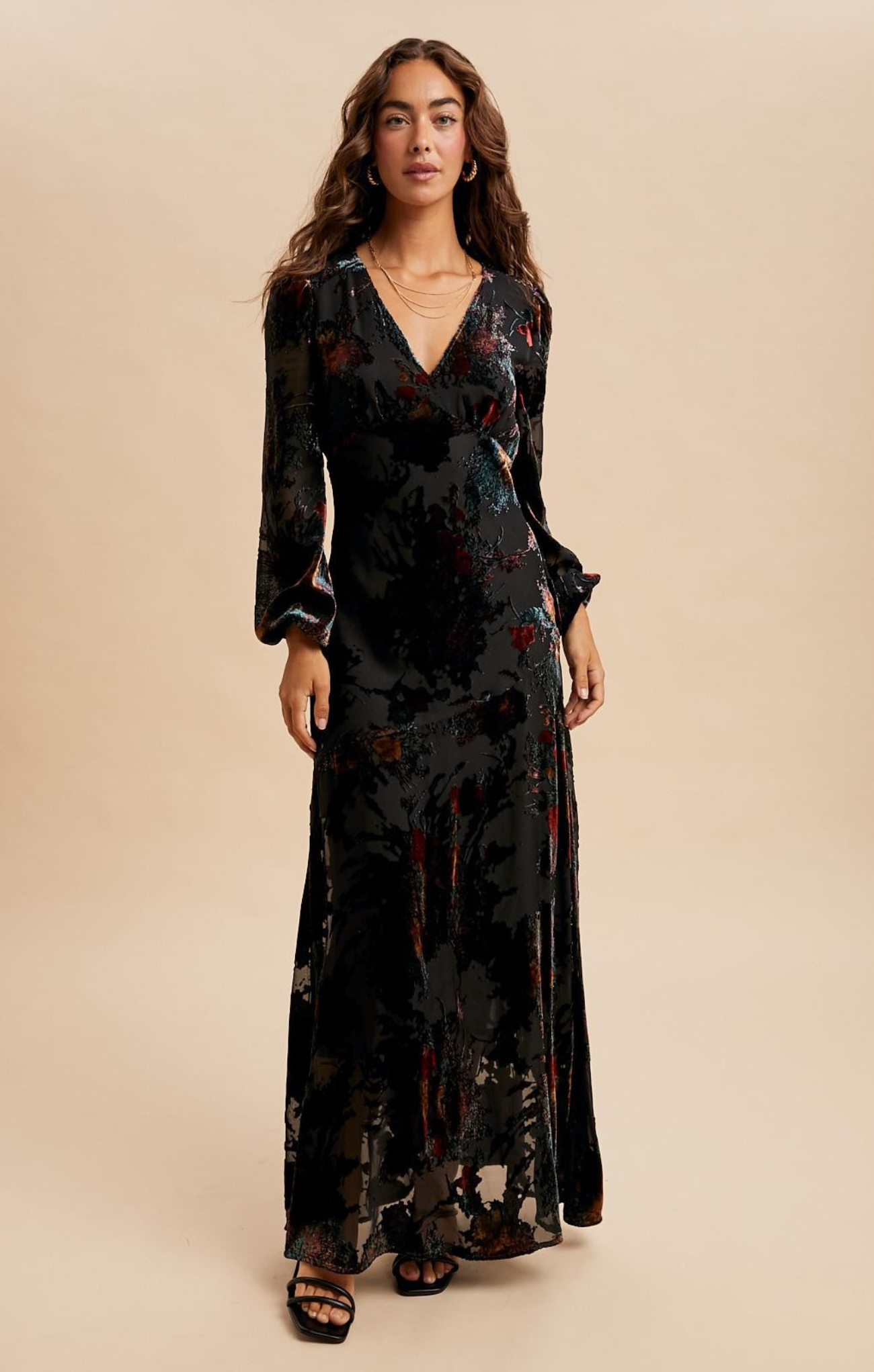 Woman wearing a black floral dress against a beige background