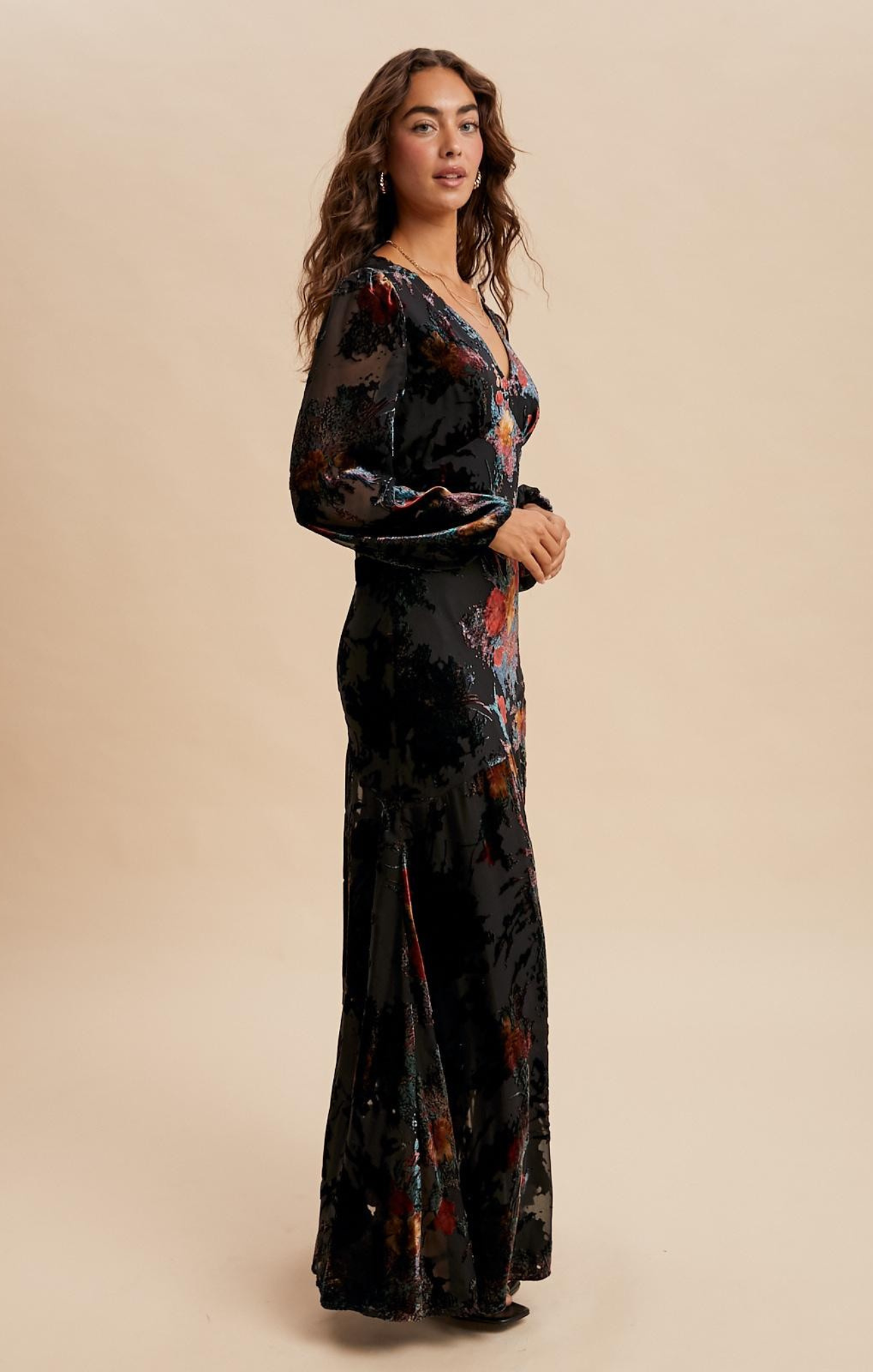 Woman wearing a black floral dress against a beige background