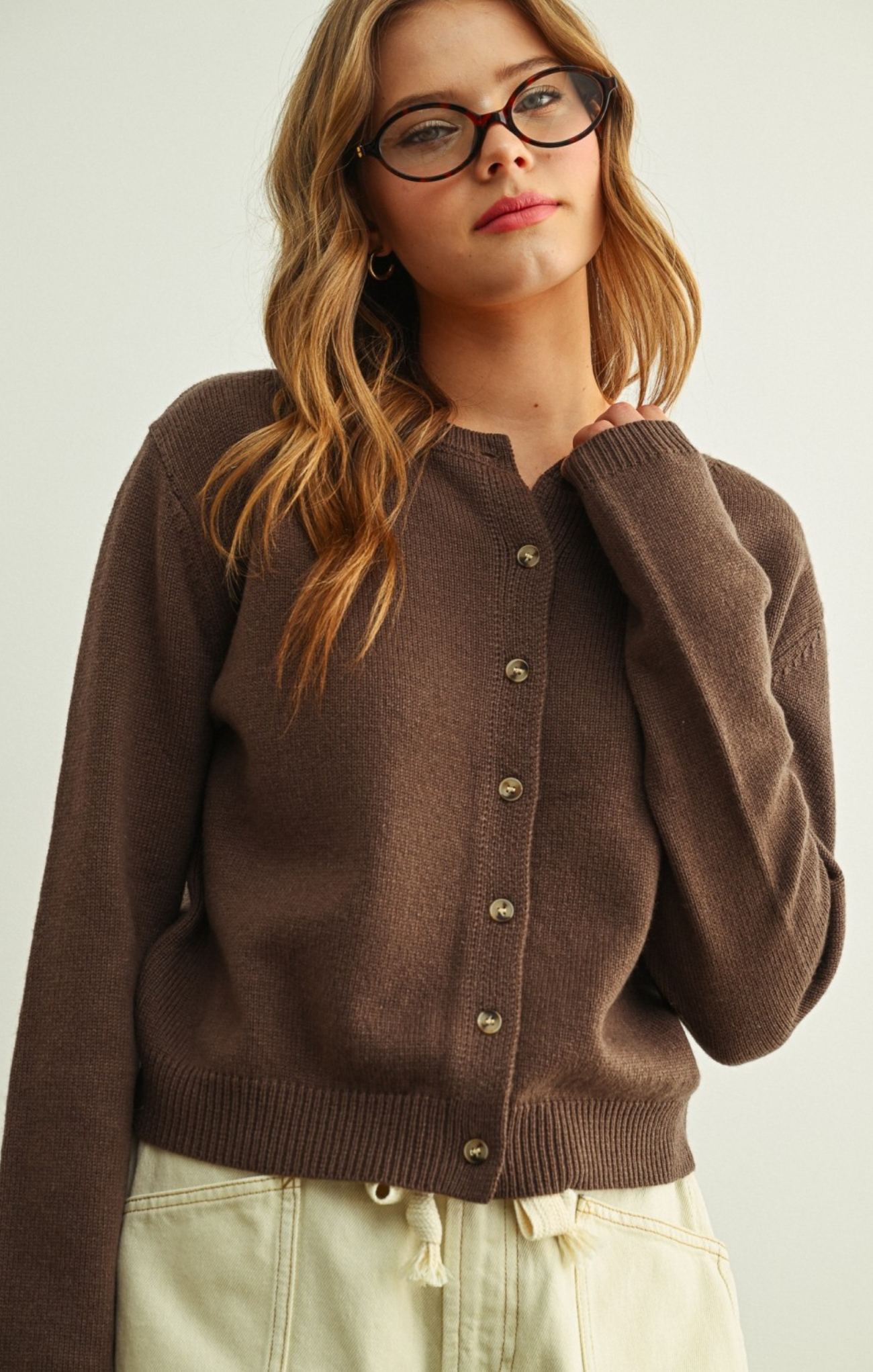 Woman wearing a brown cardigan against a plain background