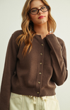 Woman wearing a brown cardigan against a plain background