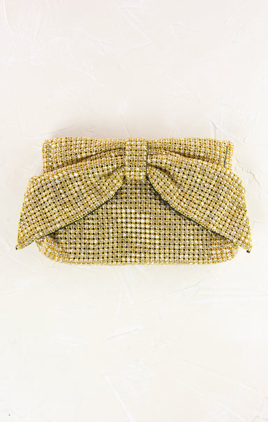 Gold beaded clutch with a bow on a white background