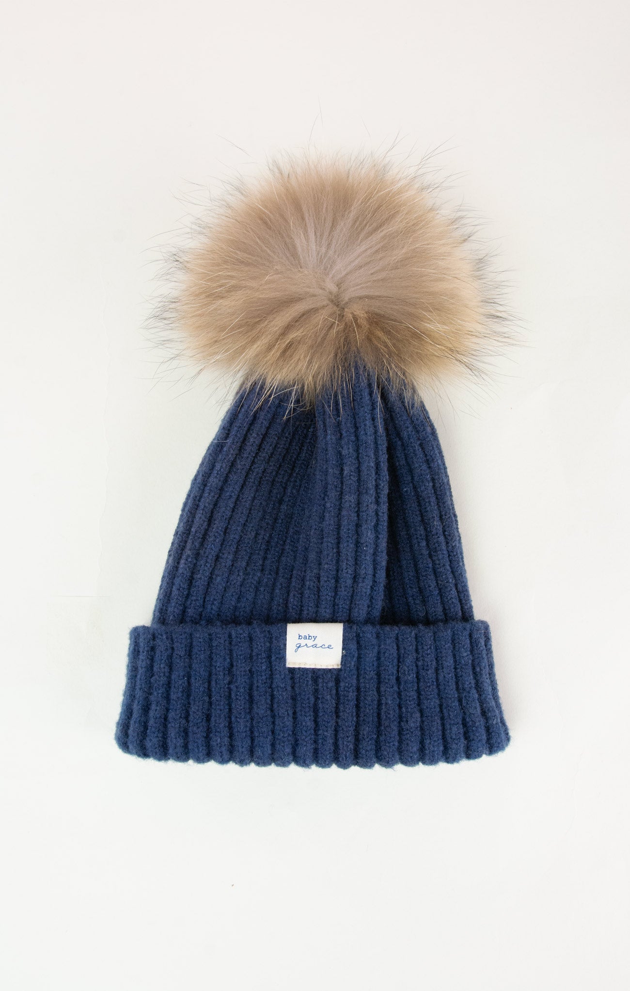Blue knit beanie with a fur pom-pom on a white background