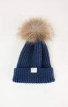Blue knit beanie with a fur pom-pom on a white background