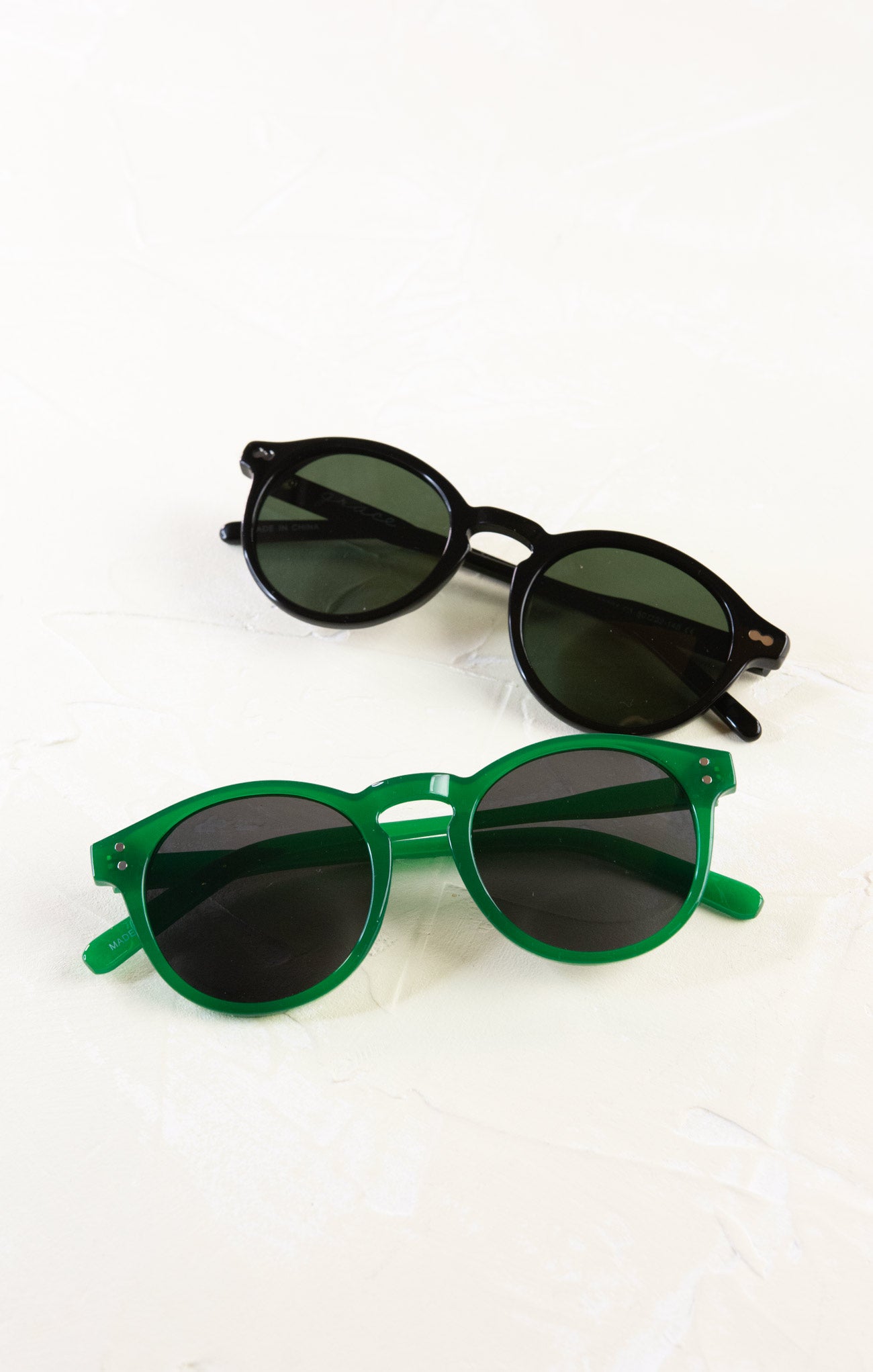 Two pairs of sunglasses, one green and one black, on a white background.