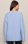 Light blue sweater worn by a person on a beige background