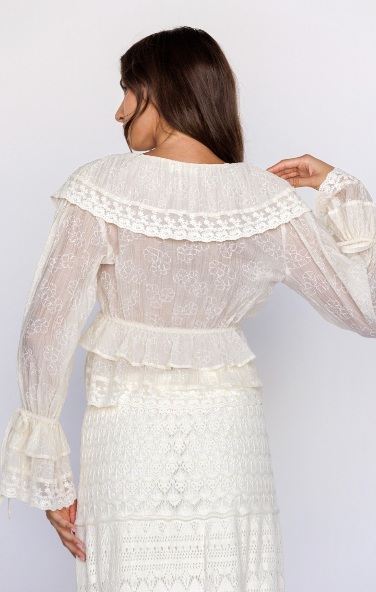 Woman wearing a white lace dress against a plain background