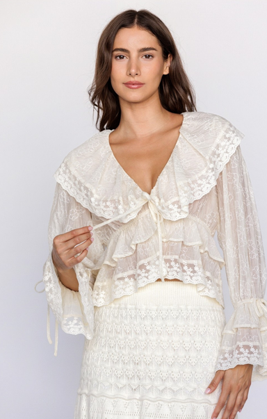 Woman wearing a white lace top and skirt against a plain background