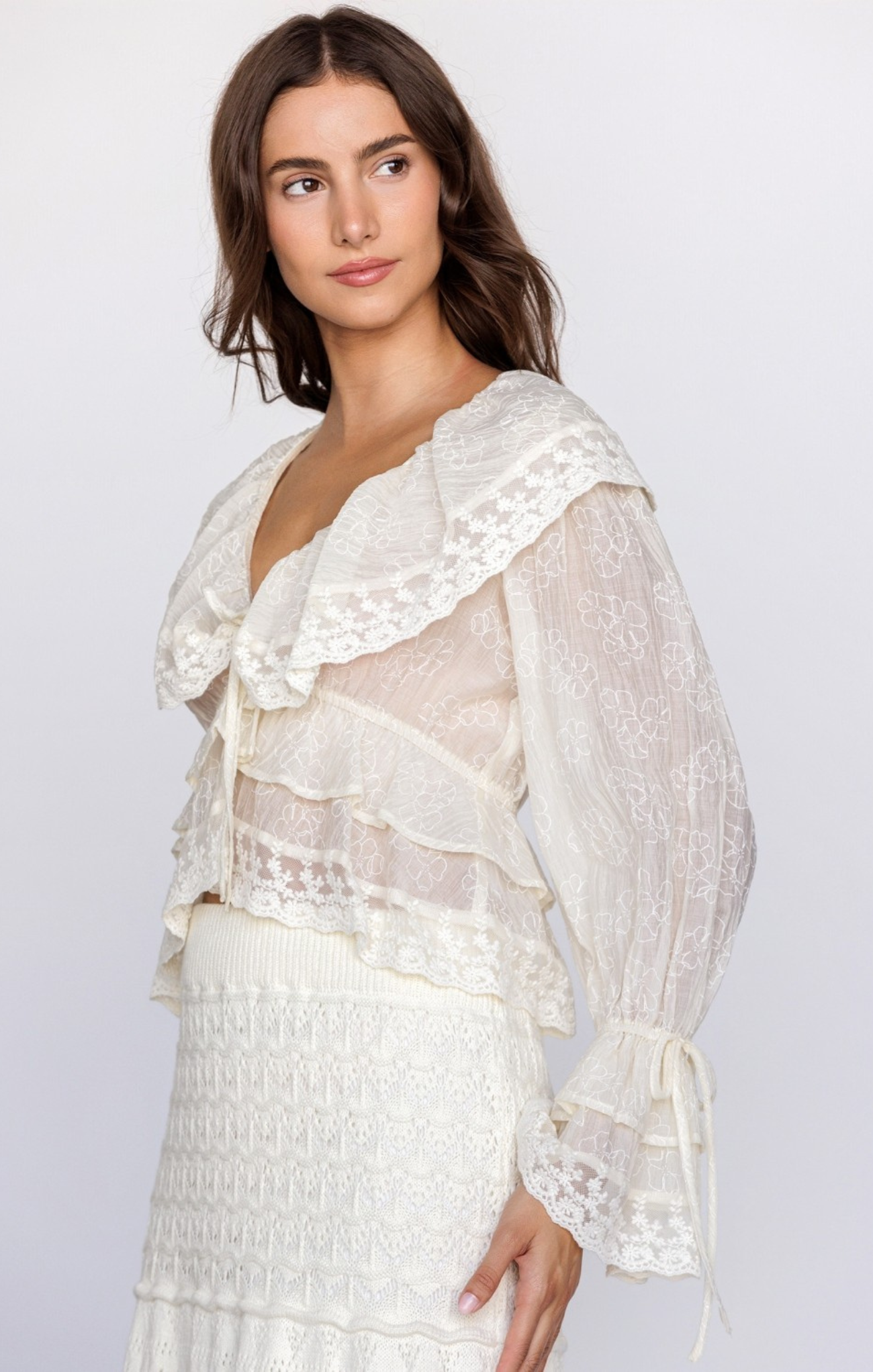 Woman wearing a white lace top and skirt set on a plain background