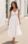 Woman wearing a white dress standing on a sidewalk.