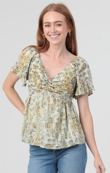 Woman wearing a floral blouse with ruffled sleeves on a plain background