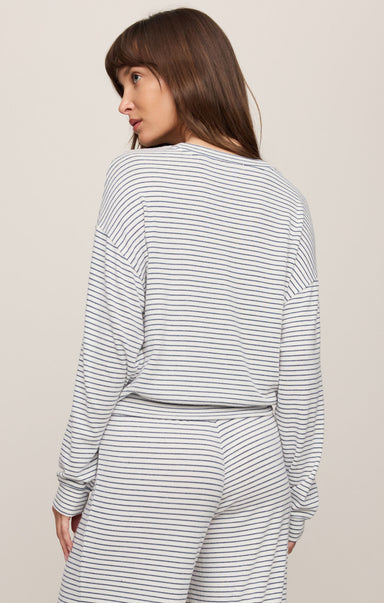 Woman wearing a striped long-sleeve top and pants on a plain background