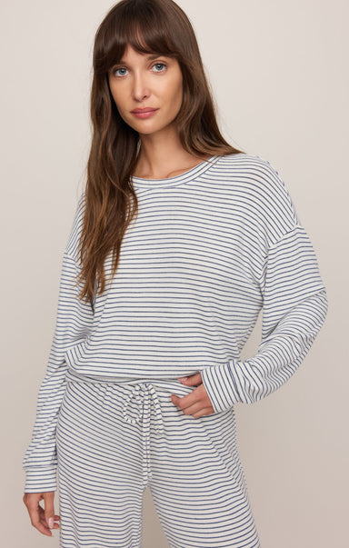 Woman wearing a striped long-sleeve top and pants on a beige background