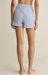 Person wearing blue checkered shorts on a beige background