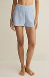 Person wearing blue checkered shorts on a beige background
