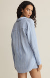 Woman wearing a blue checkered shirt against a beige background