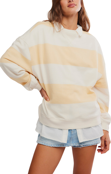 Woman wearing a cream and yellow striped sweater with denim shorts on a white background