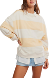 Woman wearing a cream and yellow striped sweater with denim shorts on a white background