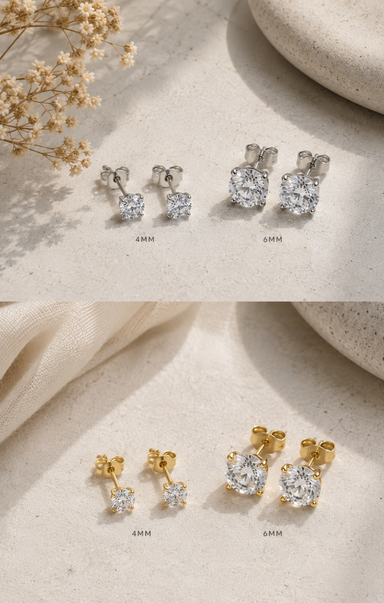 Pair of diamond stud earrings in gold and silver on a textured beige surface with dried flowers.