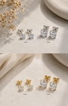 Pair of diamond stud earrings in gold and silver on a textured beige surface with dried flowers.