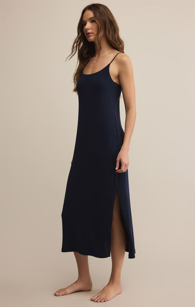 A woman wearing a navy, sleeveless, midi-length dress with a scoop neckline and spaghetti straps. The dress appears to be made of a lightweight, soft fabric and has a regular fit.