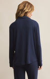 A woman wearing a navy blue, collared, long-sleeved button-front rib top with a relaxed fit.