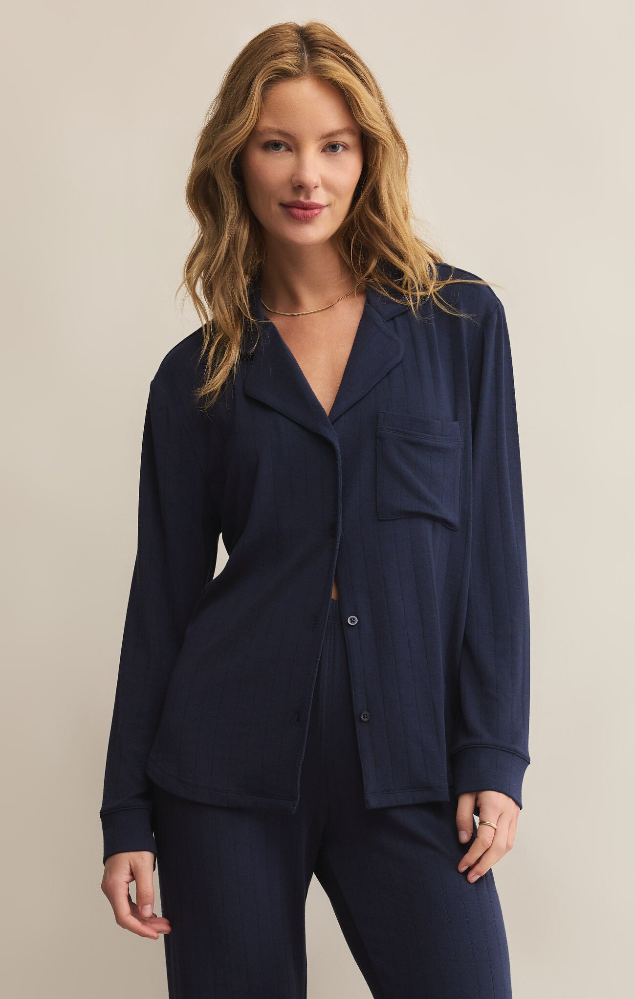 A woman wearing a navy blue, collared, long-sleeved button-front rib top with a relaxed fit.