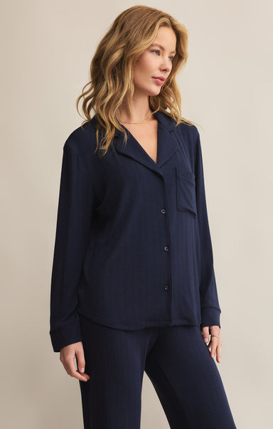 A woman wearing a navy blue, collared, long-sleeved button-front rib top with a relaxed fit.