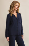 A woman wearing a navy blue, collared, long-sleeved button-front rib top with a relaxed fit.