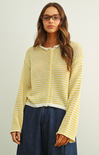 Woman wearing a yellow striped sweater and blue pants against a plain background