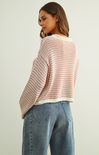 Woman wearing a striped sweater and jeans against a plain background