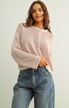 Woman wearing a striped sweater and jeans on a plain background