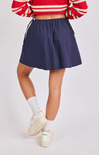 Person wearing a red and white striped sweater, navy skirt, and white sneakers on a light gray background