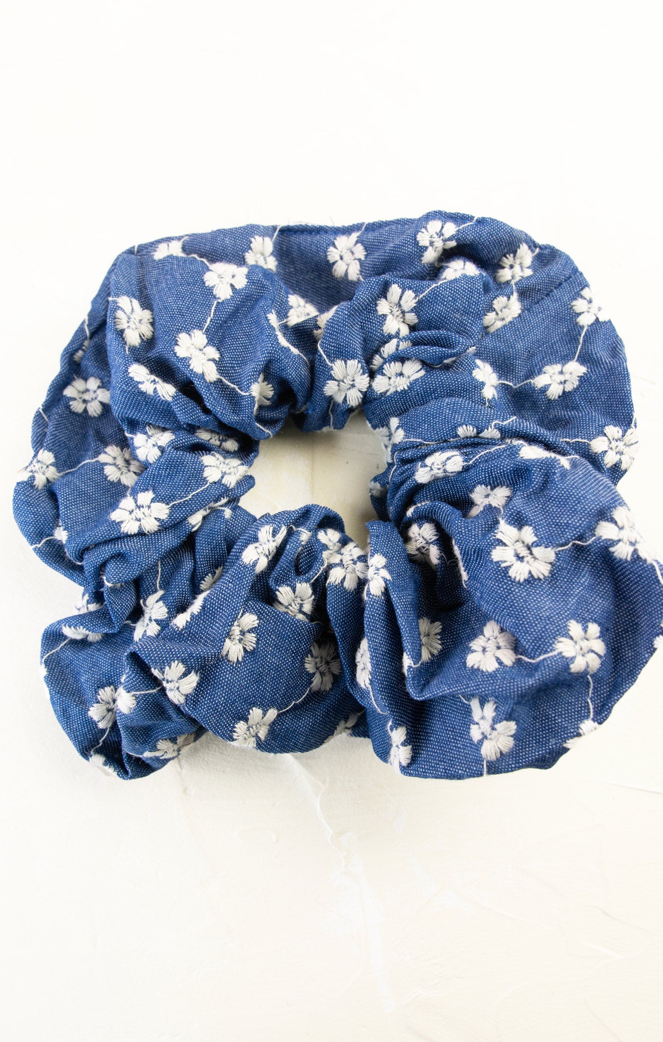 Blue scrunchie with white floral pattern on a white background