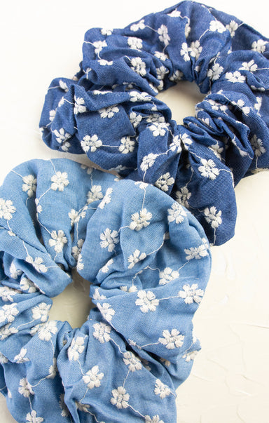 Two blue scrunchies with white floral patterns on a white background