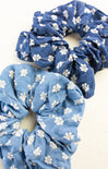 Two blue scrunchies with white floral patterns on a white background