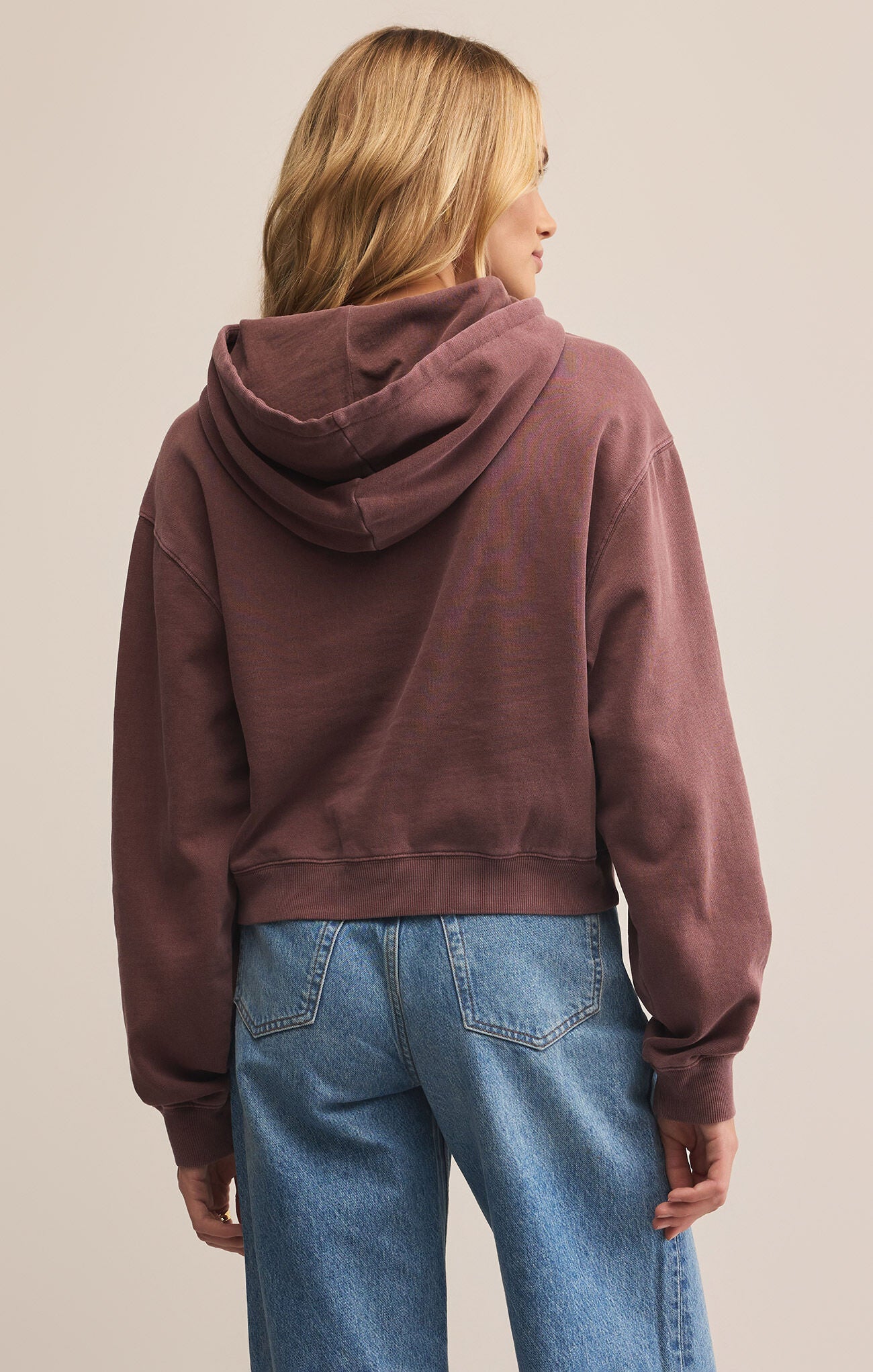 A woman wearing a purple hooded long-sleeve sweatshirt with a kangaroo pocket.