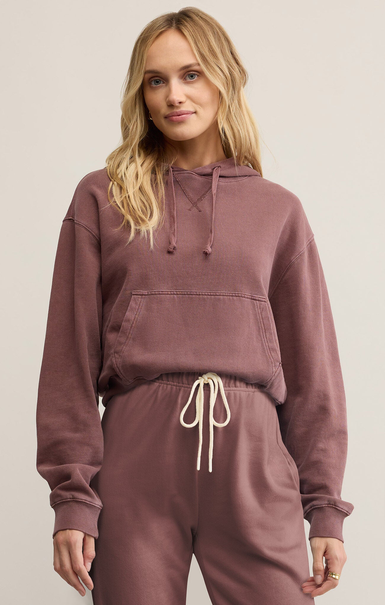 A woman wearing a purple hooded long-sleeve sweatshirt with a kangaroo pocket.