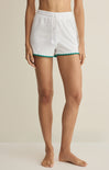 White shorts with green trim worn by a person on a beige background