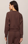 Woman wearing a brown sweatshirt and pants with white stripes on a beige background