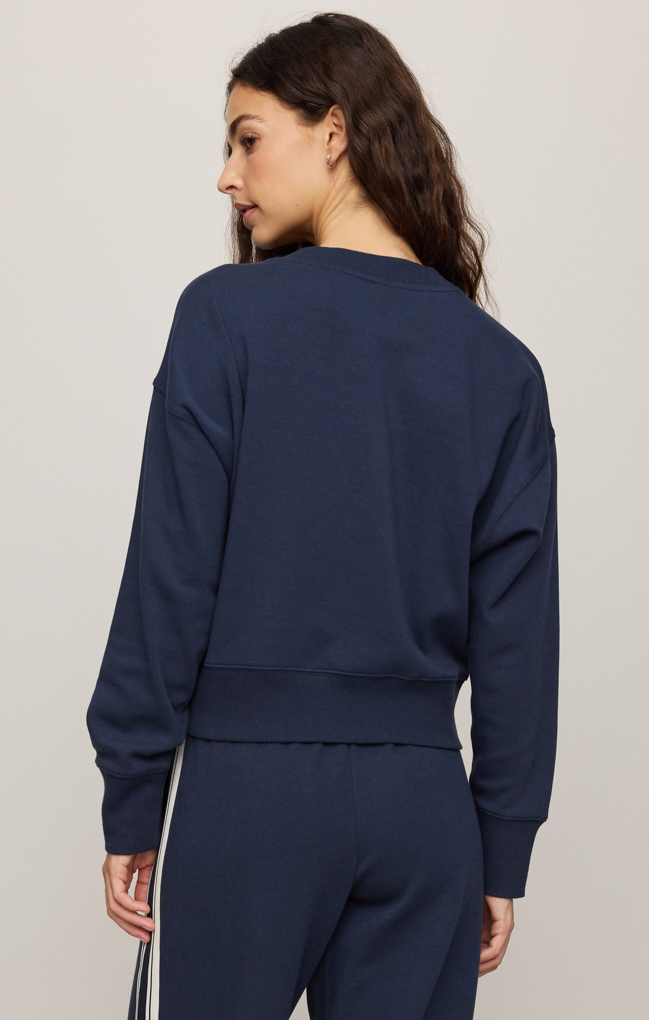 Person wearing a navy blue sweatshirt and pants on a light gray background