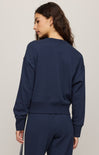 Person wearing a navy blue sweatshirt and pants on a light gray background