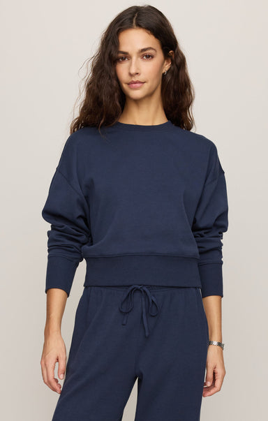 Woman wearing a navy blue outfit on a plain background