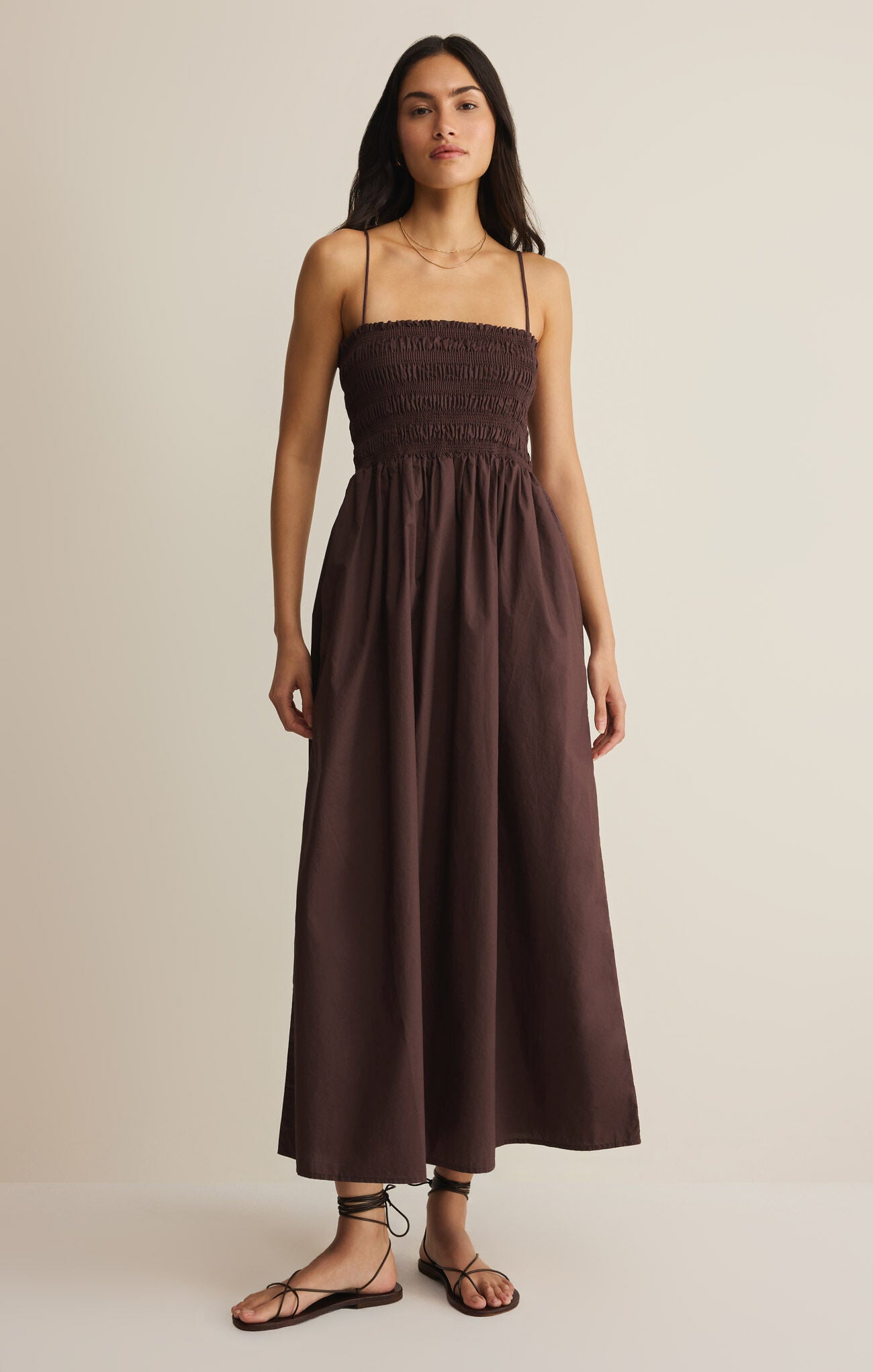 Woman wearing a brown dress against a beige background