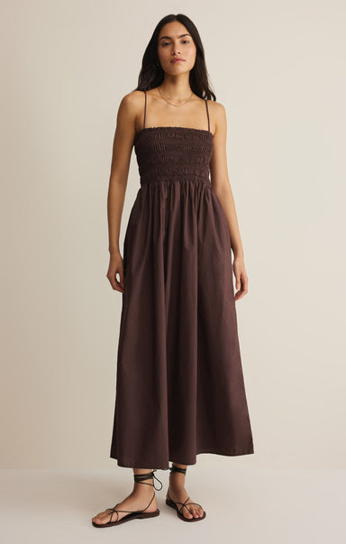 Woman wearing a brown dress against a beige background