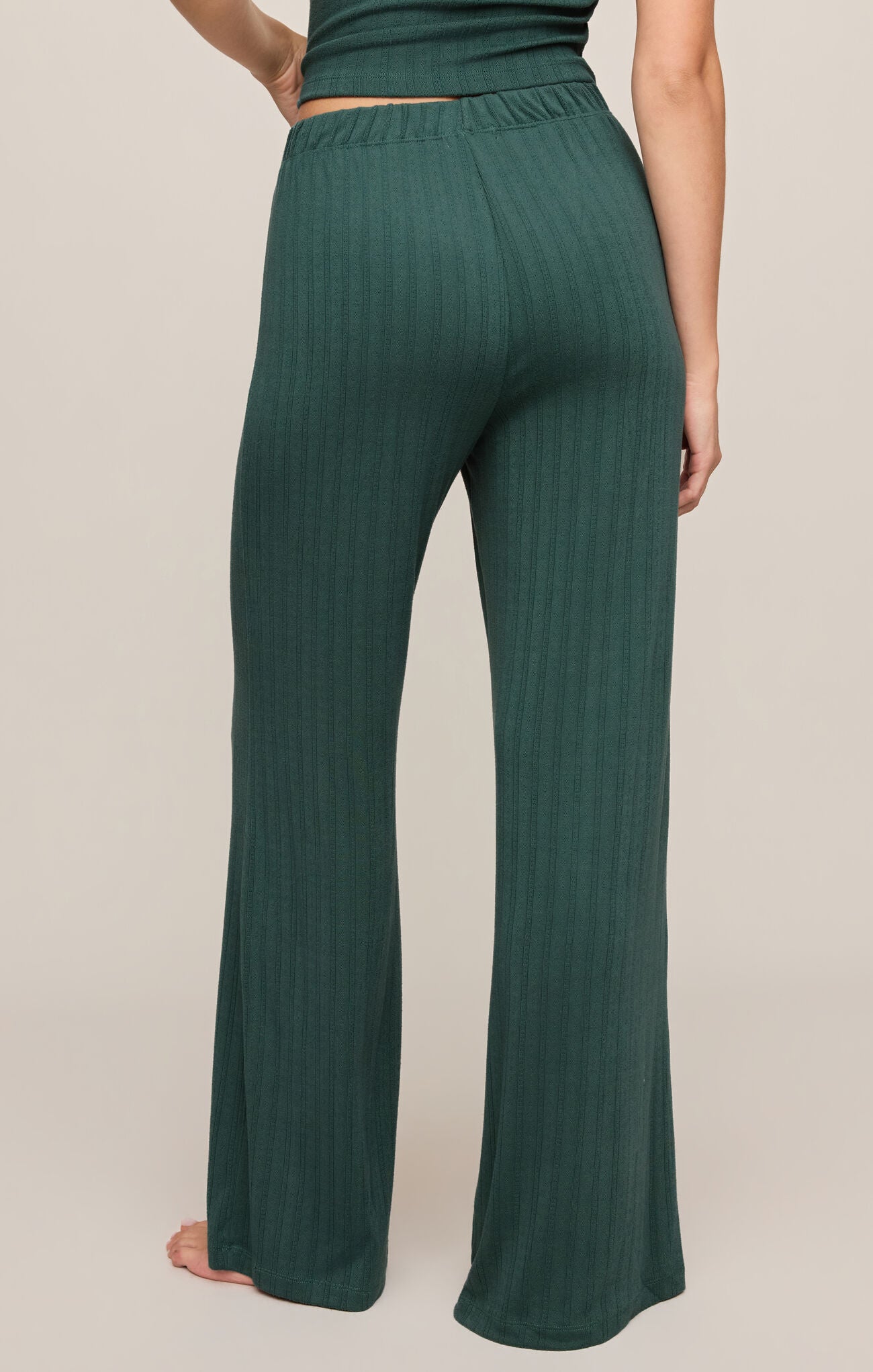 Green ribbed pants worn by a person on a beige background
