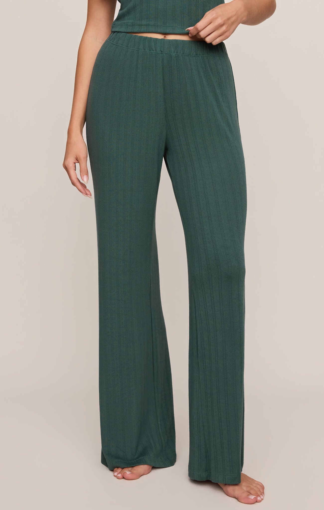 Person wearing teal ribbed lounge pants on a beige background