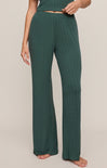 Person wearing teal ribbed lounge pants on a beige background