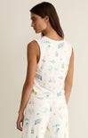 Woman wearing a sleeveless top with colorful graphic design on a beige background