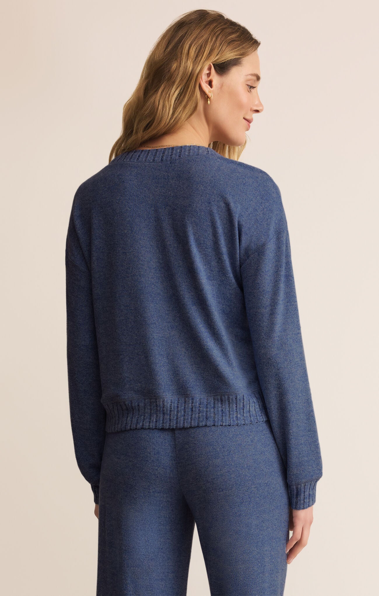 Woman wearing a blue sweater and pants on a beige background