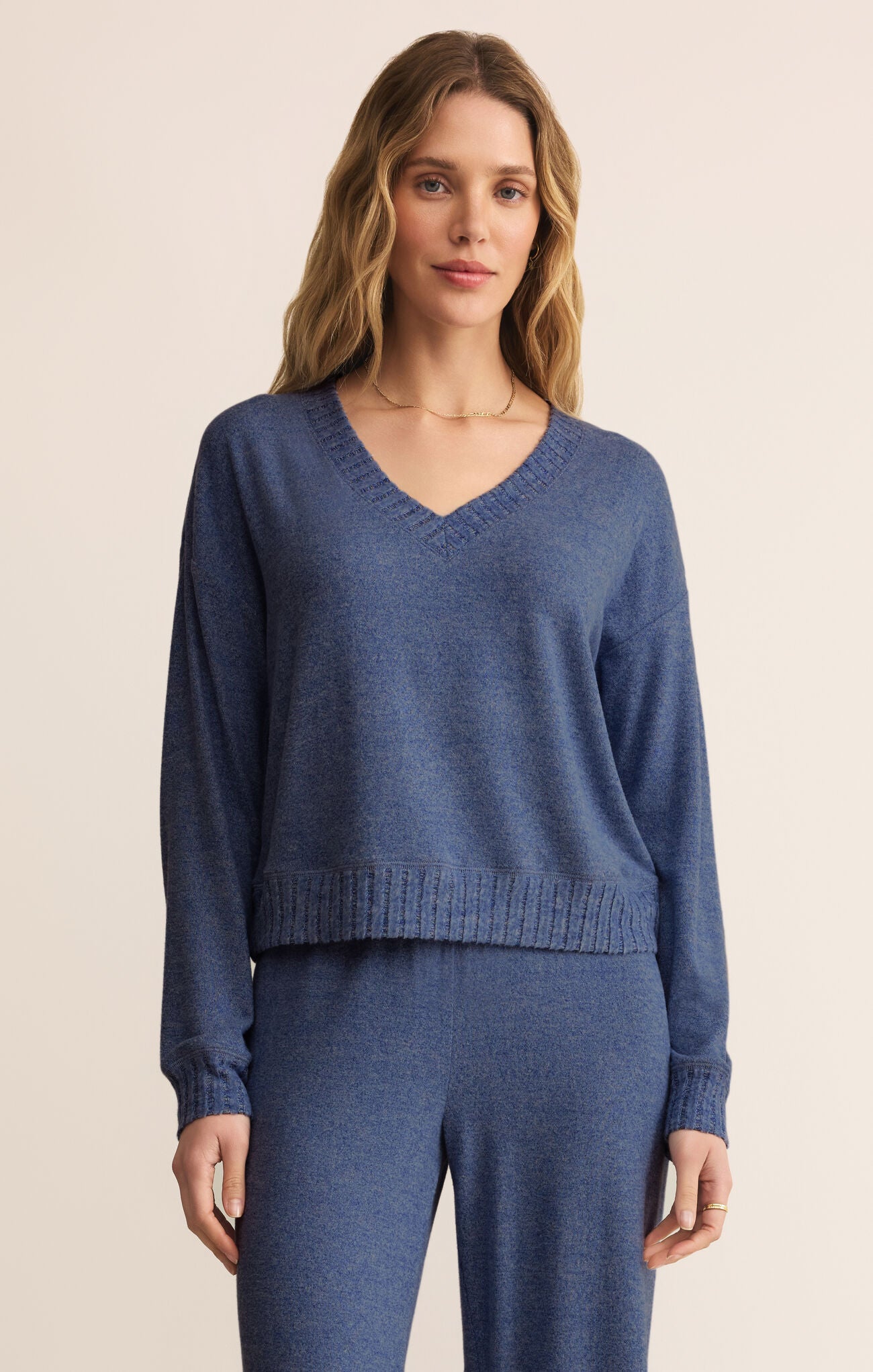 Woman wearing a blue sweater and pants on a beige background